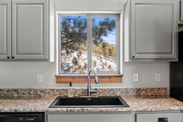 kitchen featuring a textured wall, black dishwasher, a sink, and dishwasher