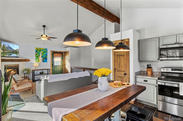 kitchen with stainless steel appliances, gray cabinets, beamed ceiling, a glass covered fireplace, and pendant lighting