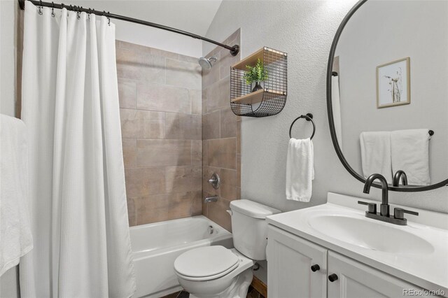 bathroom with a textured wall, shower / tub combo, vanity, and toilet