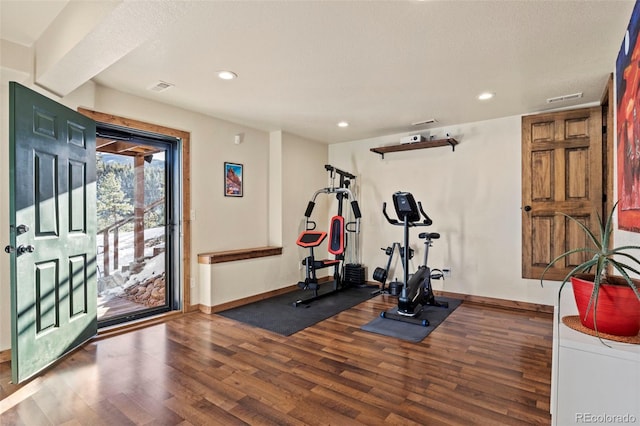 workout area featuring visible vents, baseboards, and wood finished floors