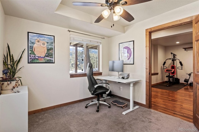 carpeted home office with ceiling fan and baseboards