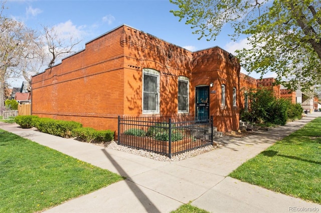 view of side of home with a fenced front yard, a yard, and brick siding