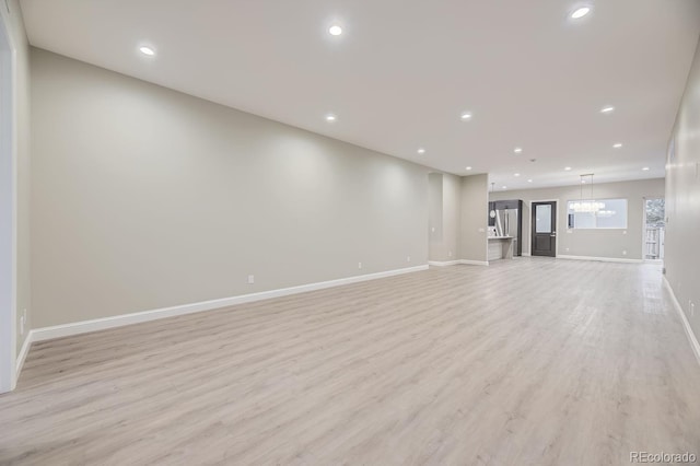 unfurnished living room featuring light hardwood / wood-style flooring and a chandelier