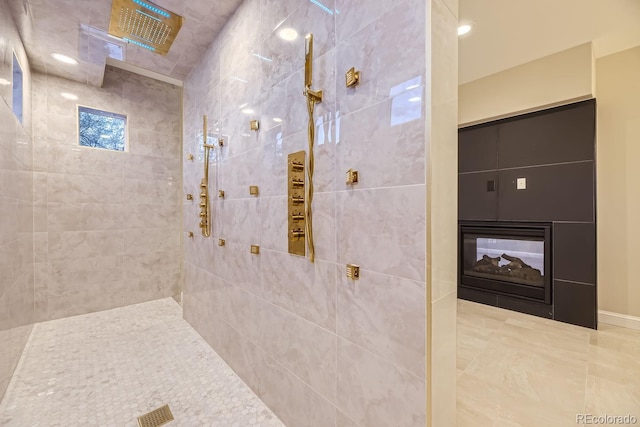 bathroom with a multi sided fireplace and tiled shower