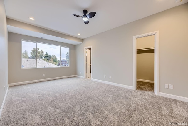 unfurnished bedroom featuring carpet, ceiling fan, a walk in closet, and a closet