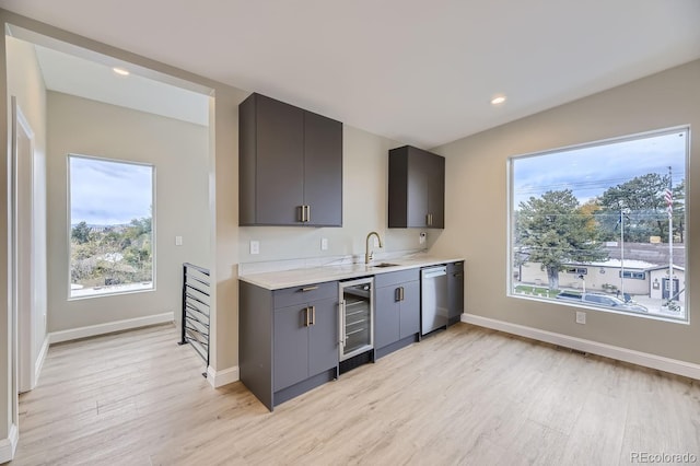 kitchen with stainless steel dishwasher, beverage cooler, sink, and light wood-type flooring