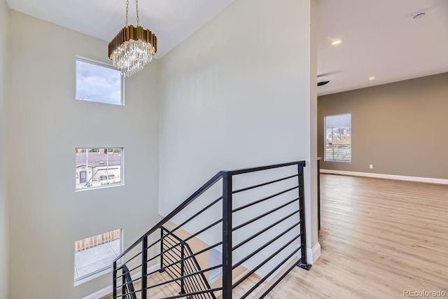 stairs with wood-type flooring and a chandelier