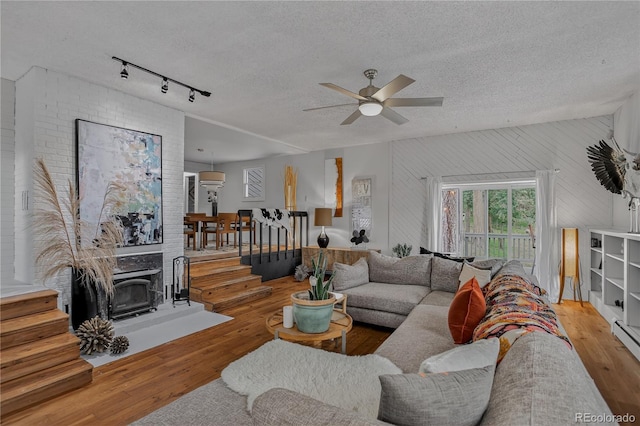 119 Yew Ln, Bailey, CO 80421 - living area with a wood stove, wood finished floors, a ceiling fan, rail lighting, and stairs