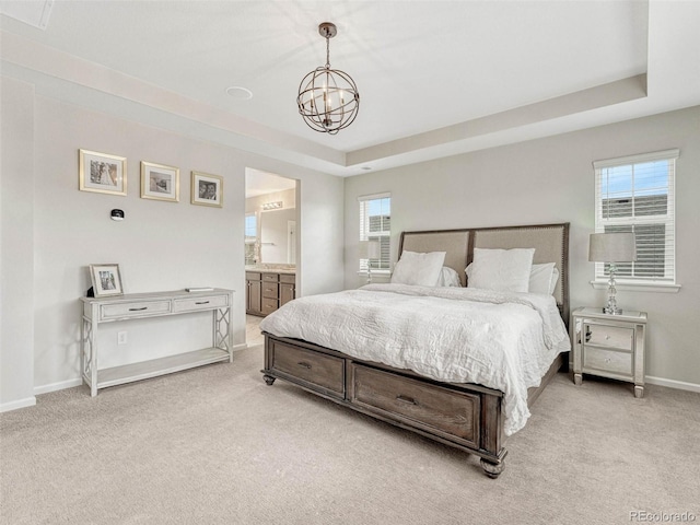 carpeted bedroom featuring multiple windows, a chandelier, connected bathroom, and a raised ceiling