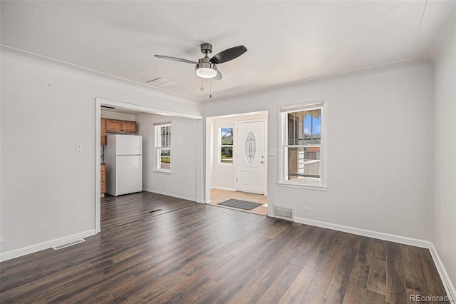 empty room with ceiling fan, visible vents, baseboards, and dark wood-type flooring
