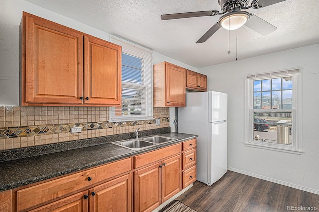 kitchen with freestanding refrigerator, dark wood-style flooring, a sink, and backsplash