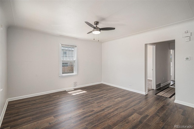 spare room featuring dark wood-style flooring, ceiling fan, visible vents, and baseboards