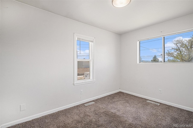 carpeted empty room featuring baseboards and visible vents