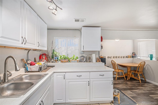 kitchen featuring visible vents, wood finished floors, light countertops, white cabinets, and a sink