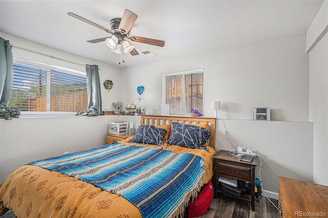 bedroom with visible vents, ceiling fan, wood finished floors, and multiple windows