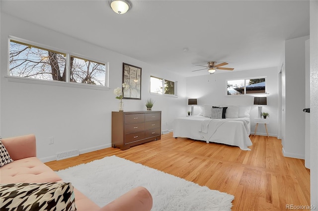 bedroom with ceiling fan, light hardwood / wood-style floors, and multiple windows