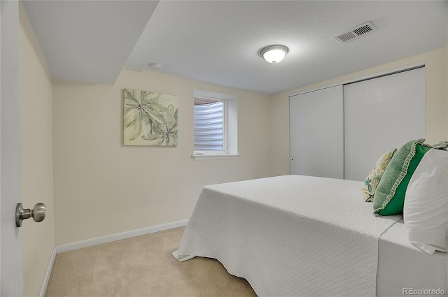 bedroom with a closet, light colored carpet, and a textured ceiling