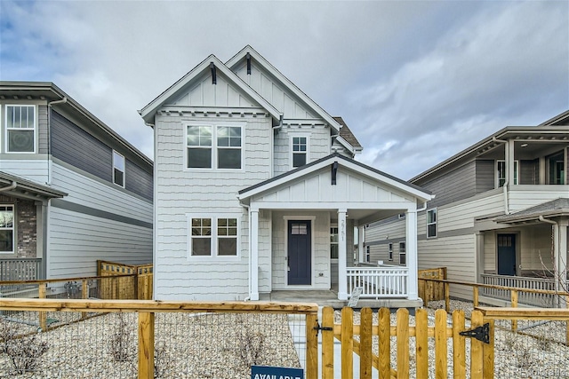 view of front facade featuring covered porch, a fenced front yard, and board and batten siding