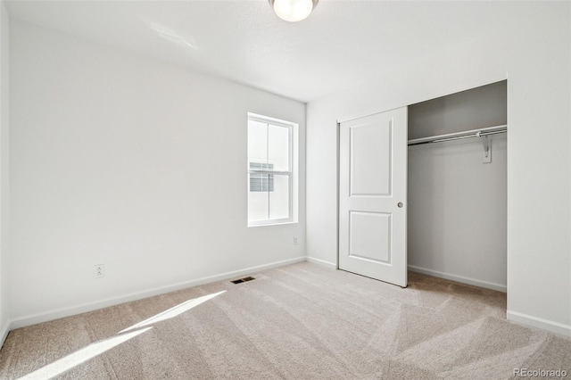 unfurnished bedroom with a closet and light carpet