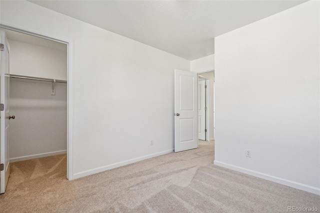 unfurnished bedroom featuring light carpet, a walk in closet, and a closet