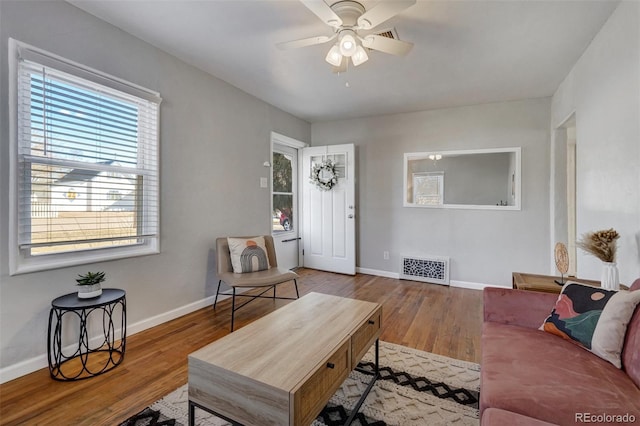 living area featuring baseboards, light wood-style flooring, visible vents, and a ceiling fan