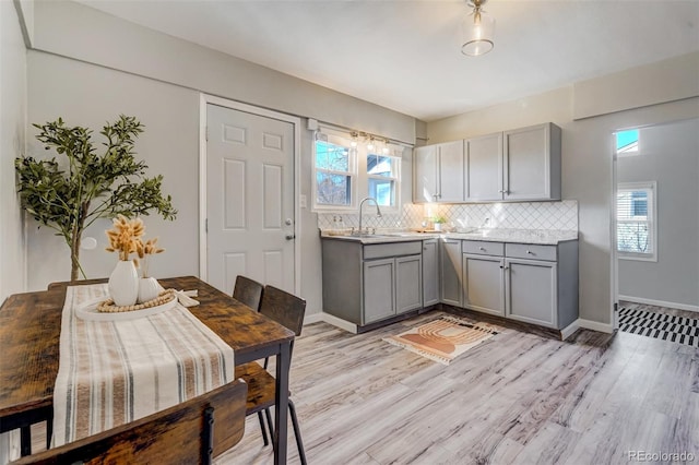 kitchen featuring light wood-style flooring, tasteful backsplash, light countertops, and gray cabinetry