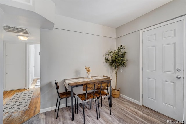 dining room featuring light wood-style floors, baseboards, and visible vents