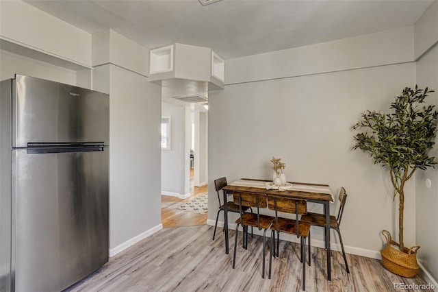 dining space with light wood-style floors and baseboards