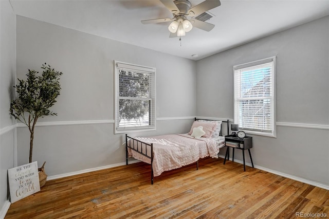 bedroom featuring a ceiling fan, baseboards, visible vents, and wood finished floors