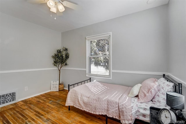 bedroom featuring baseboards, visible vents, ceiling fan, and wood finished floors