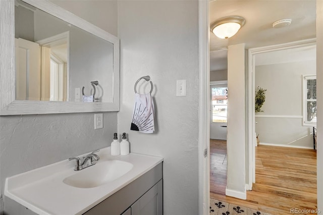 bathroom featuring a textured wall, wood finished floors, vanity, and baseboards