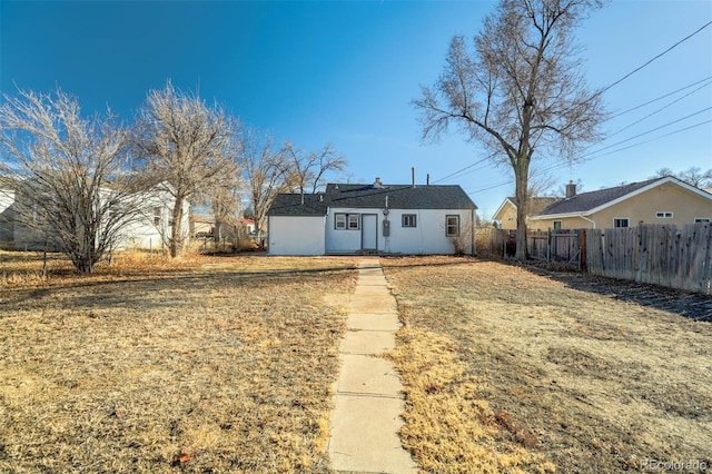 rear view of house featuring fence and a lawn