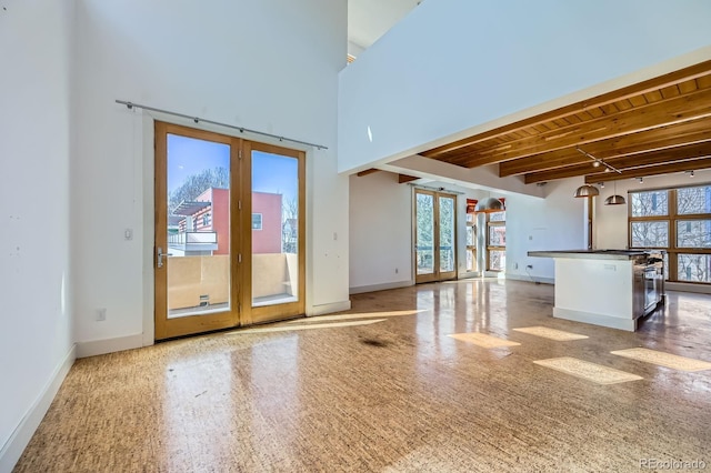 empty room featuring wooden ceiling, baseboards, french doors, beamed ceiling, and plenty of natural light