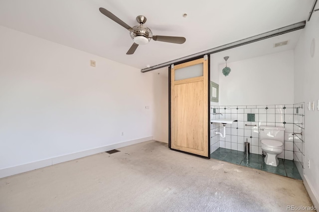 unfurnished bedroom featuring a barn door, visible vents, and baseboards