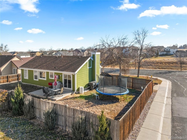 rear view of property featuring a trampoline and a patio area