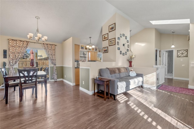 living room featuring vaulted ceiling with skylight, dark hardwood / wood-style floors, and an inviting chandelier