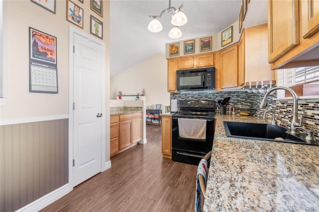 kitchen with light stone counters, sink, black appliances, decorative light fixtures, and a chandelier