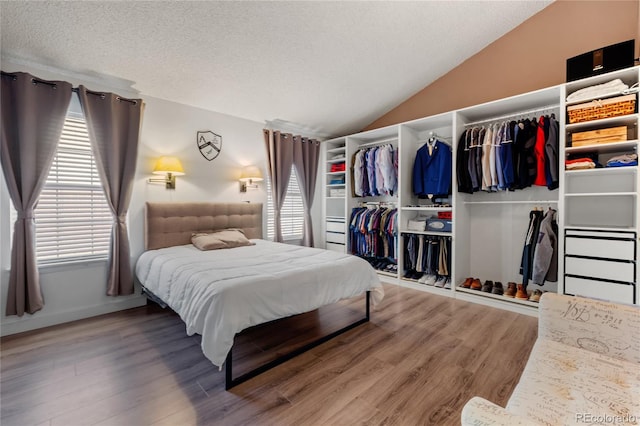 bedroom featuring multiple windows, a closet, lofted ceiling, and hardwood / wood-style flooring