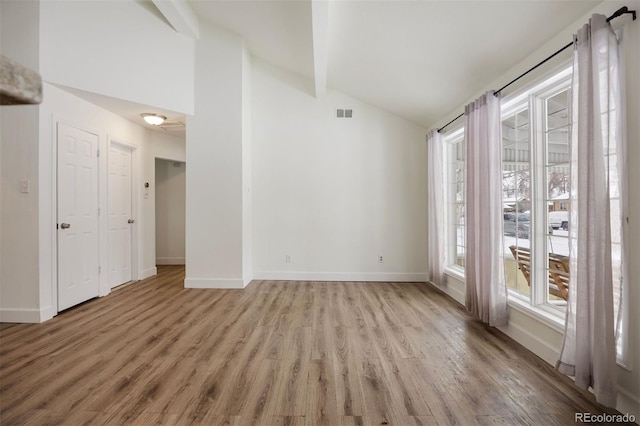 unfurnished room with light hardwood / wood-style flooring and vaulted ceiling with beams