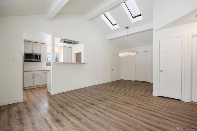 1901 Clinton St, Aurora, CO 80010 - unfurnished living room featuring a skylight, beam ceiling, light wood-style floors, baseboards, and high vaulted ceiling