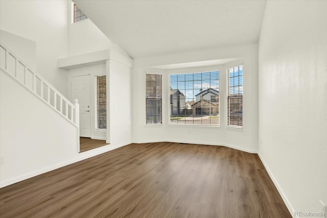 unfurnished living room featuring vaulted ceiling, stairs, baseboards, and wood finished floors