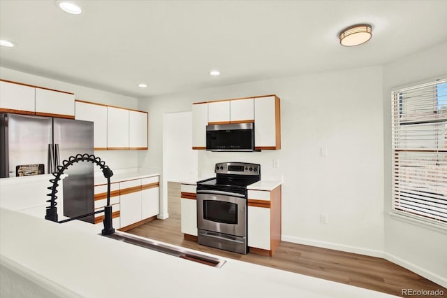 kitchen featuring light wood-style floors, white cabinets, light countertops, appliances with stainless steel finishes, and recessed lighting
