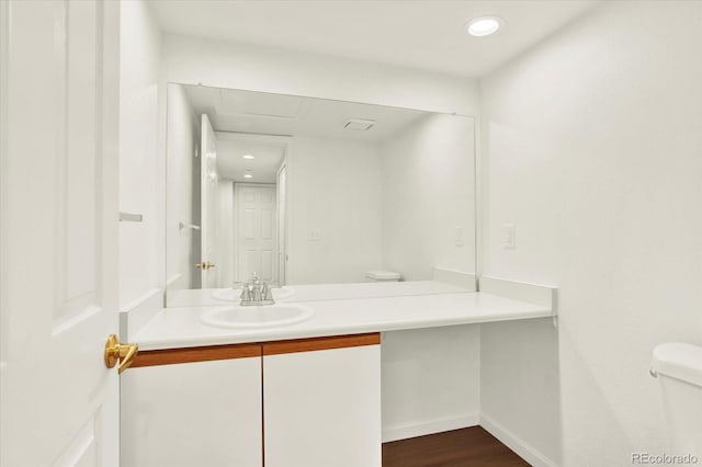 half bathroom with recessed lighting, toilet, baseboards, vanity, and wood finished floors