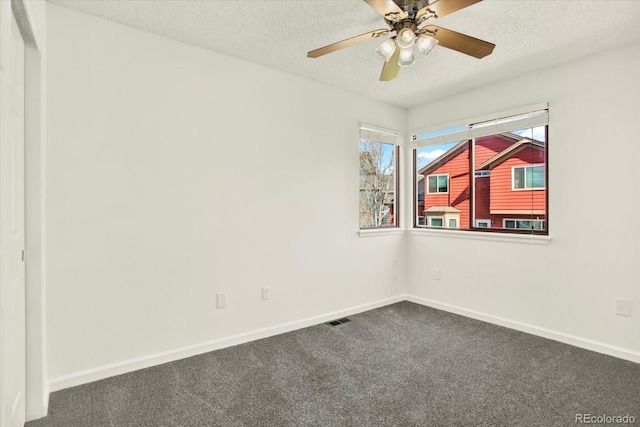 spare room with a textured ceiling, visible vents, ceiling fan, dark colored carpet, and baseboards