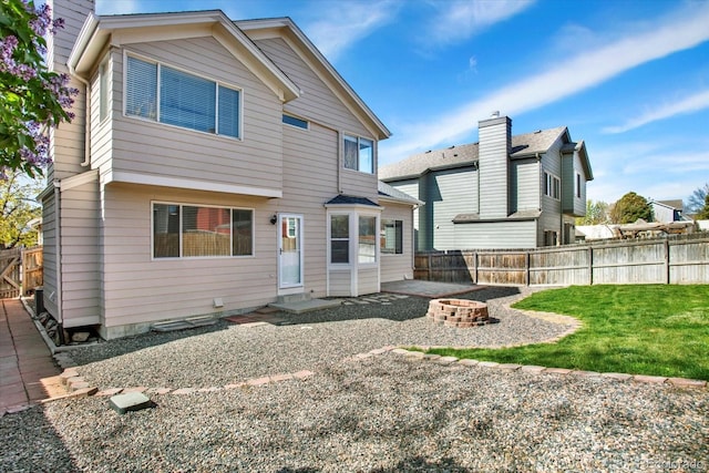 back of property with a fenced backyard, an outdoor fire pit, a patio, and a yard