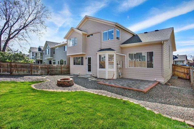 back of house featuring a lawn, an outdoor fire pit, a patio area, a shingled roof, and a fenced backyard