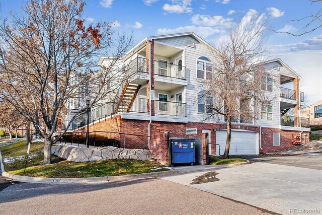 1648 S Cole St Unit B7, Lakewood, CO 80228 - townhome / multi-family property featuring an attached garage, driveway, brick siding, and a balcony