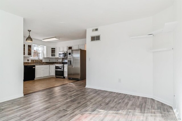 1648 S Cole St Unit B7, Lakewood, CO 80228 - kitchen featuring appliances with stainless steel finishes, wood finished floors, glass insert cabinets, white cabinets, and dark countertops