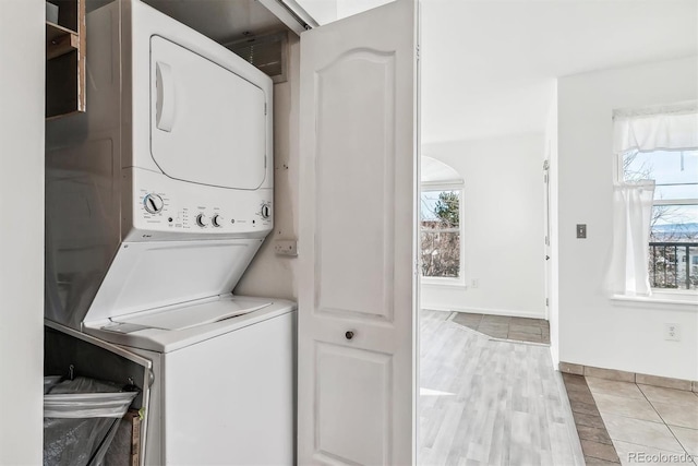 laundry area with stacked washer / dryer and light wood-type flooring