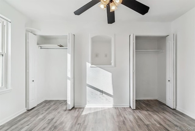 unfurnished bedroom with ceiling fan, light hardwood / wood-style flooring, and two closets